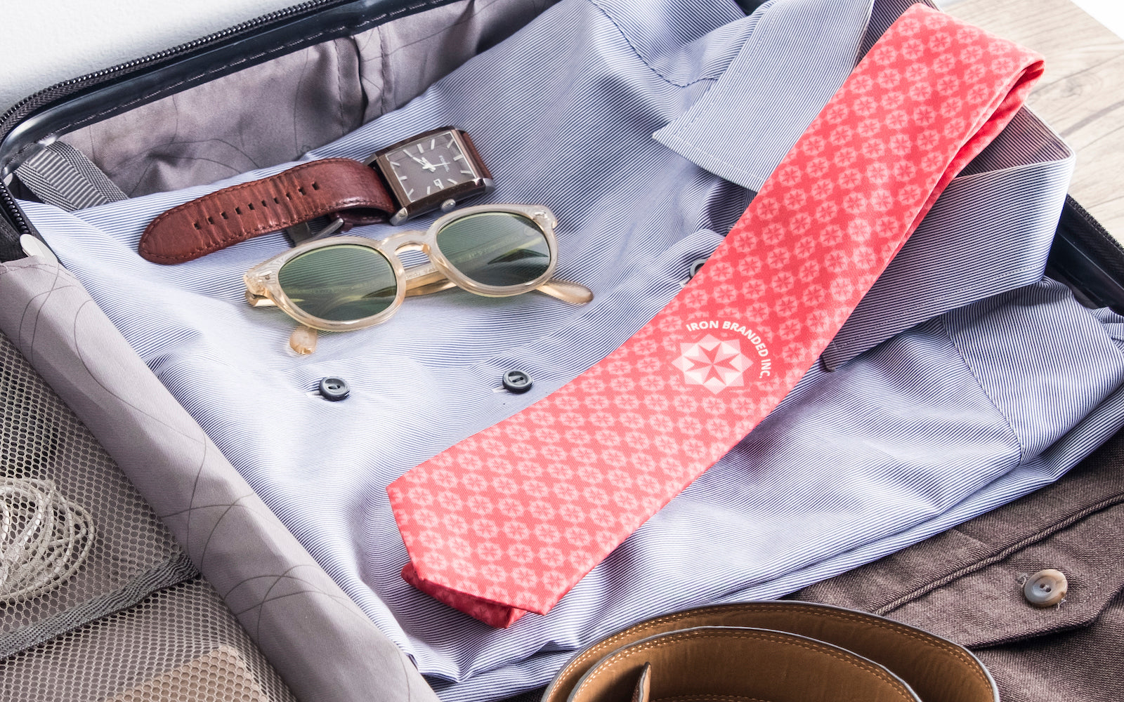 Red necktie in suitcase featuring a logo