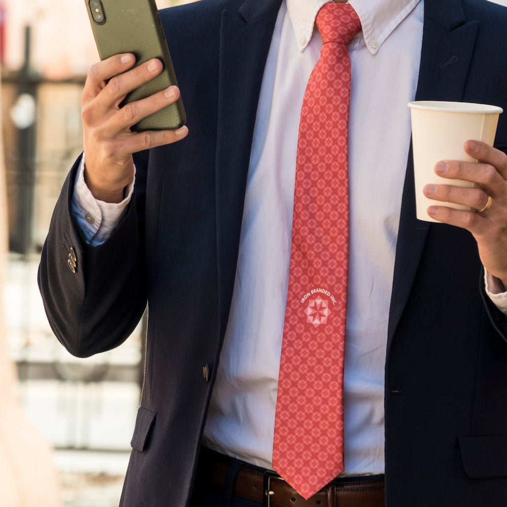 man wearing red logo necktie with phone and cup in hands